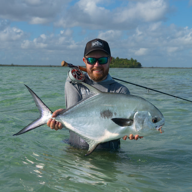 Leende sportfiskare med solglasögon håller stor silverfisk i klart vatten, Ascension Bay Mexiko, perfekt för fiskeresa.