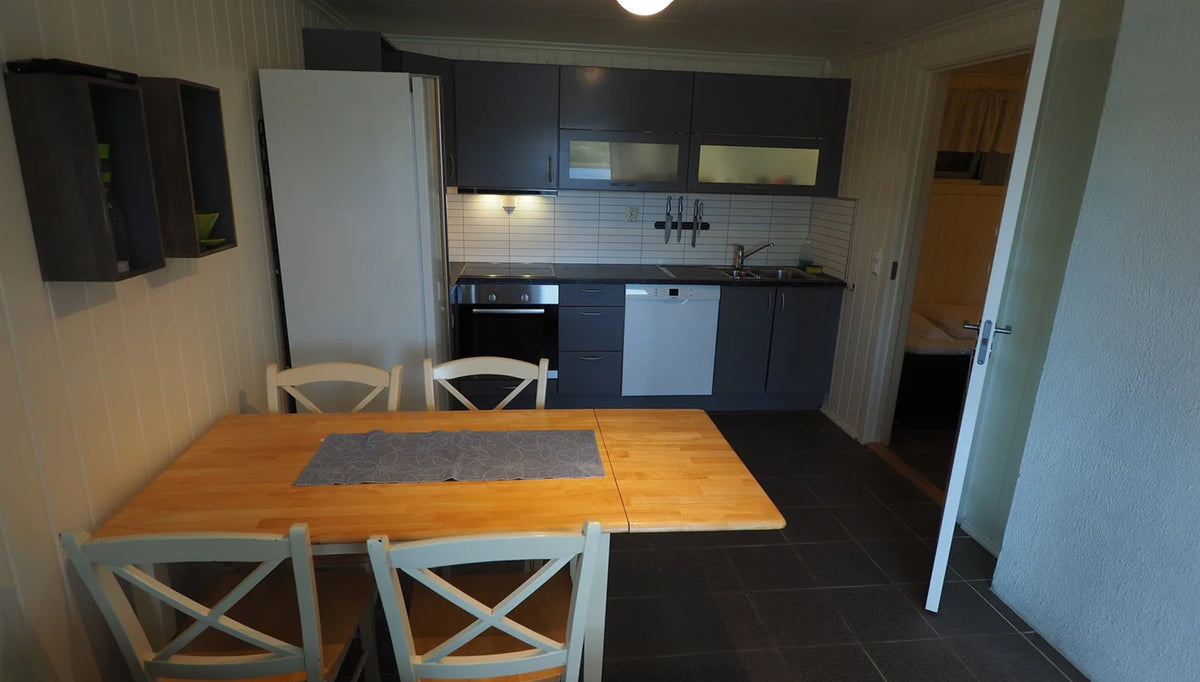 Kök med grå skåp, vitt kakel och moderna vitvaror. Matbord för fyra-idealisk plats för fiskeresor och sportfiskare.
