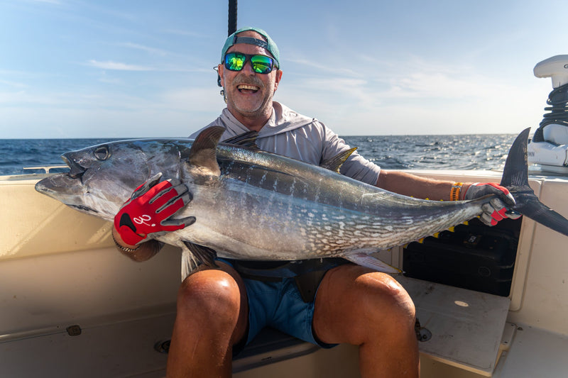 Leende fiskare med en stor blåfenad tonfisk i famnen ombord på båten under fiske i Spanien