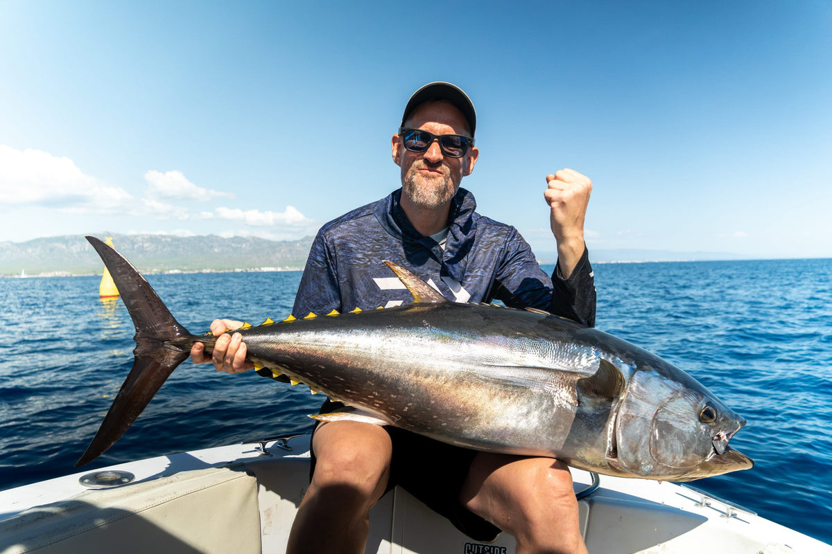 Jublande fiskare med en blåfenad tonfisk i båten framför de spanska kustbergen vid Ebrodeltat
