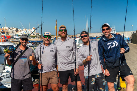 Guide och fyra fiskare med tonfiskspön och rullar på bryggan i hamnen inför en dag med fiske i Spanien