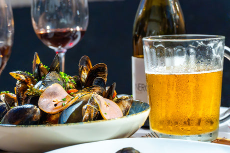Skål med ångade blåmusslor, ett kallt glas öl och vin på restaurang vid den spanska Medelhavskusten