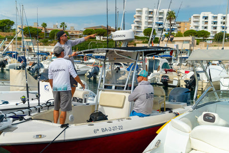 Guide pekar ut riktningen till gruppen i fiskebåten i småbåtshamnen inför en dag med fiske i Spanien