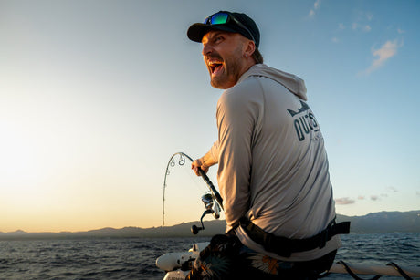 Fiskare jublar mitt i drillen av en tonfisk med kustbergen i kvällsljus – fiske i Spanien